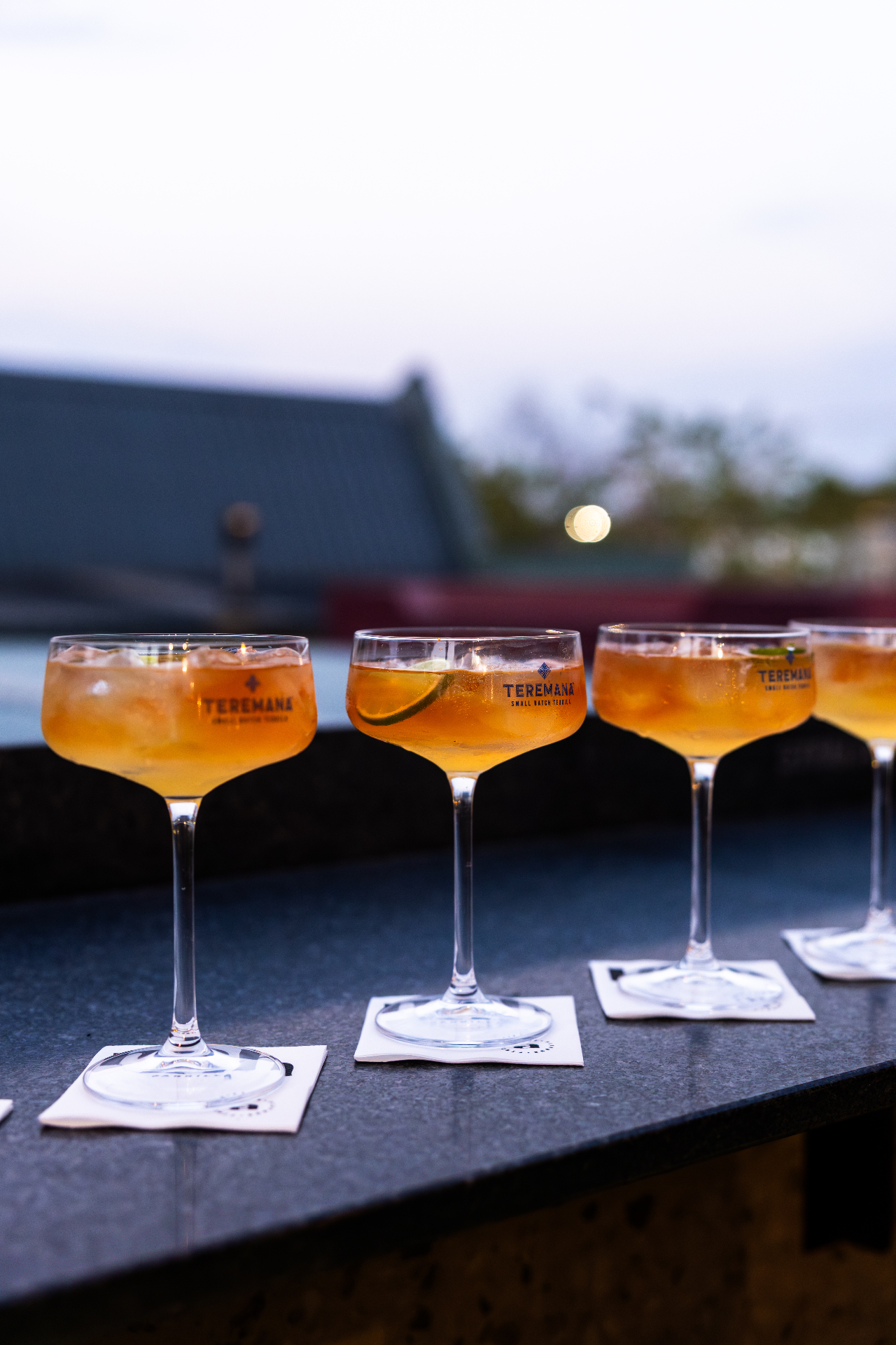 Signature cocktails lined up on the bar at dusk